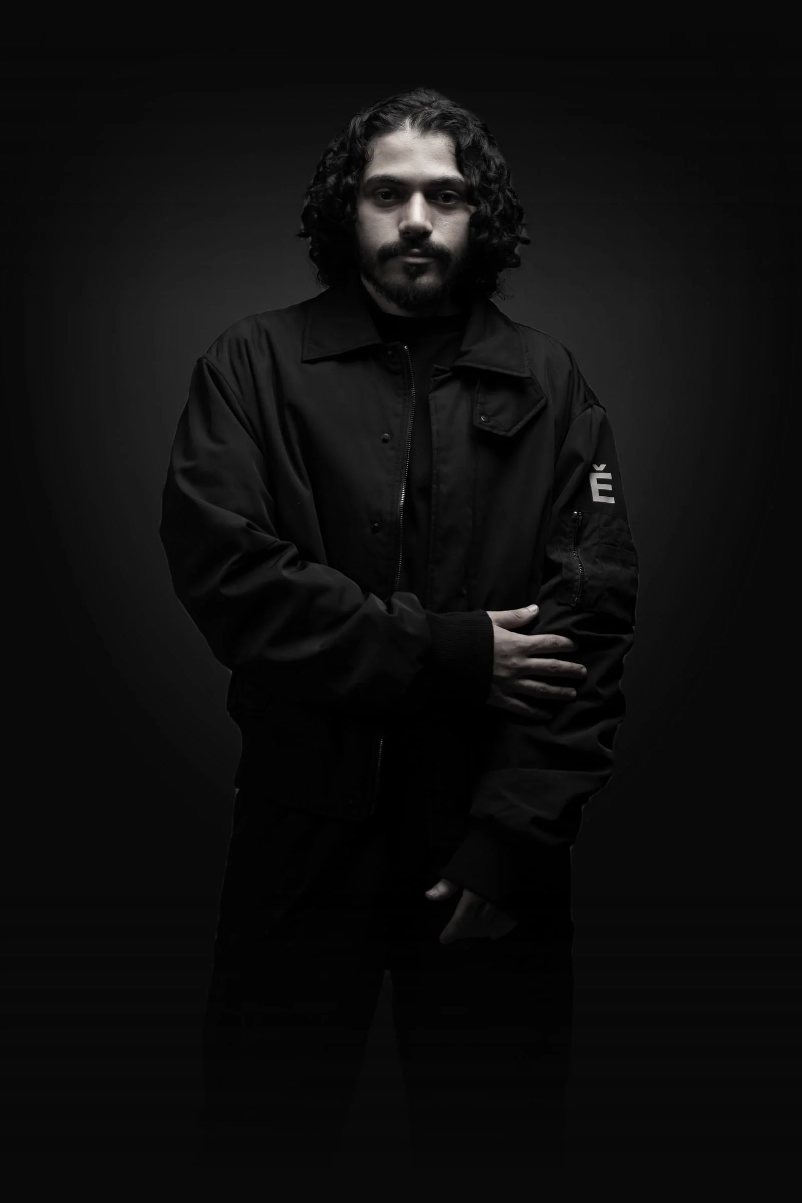 SOUL, a studio portrait in black and white: long curly hair, arms folded, dressed in black
