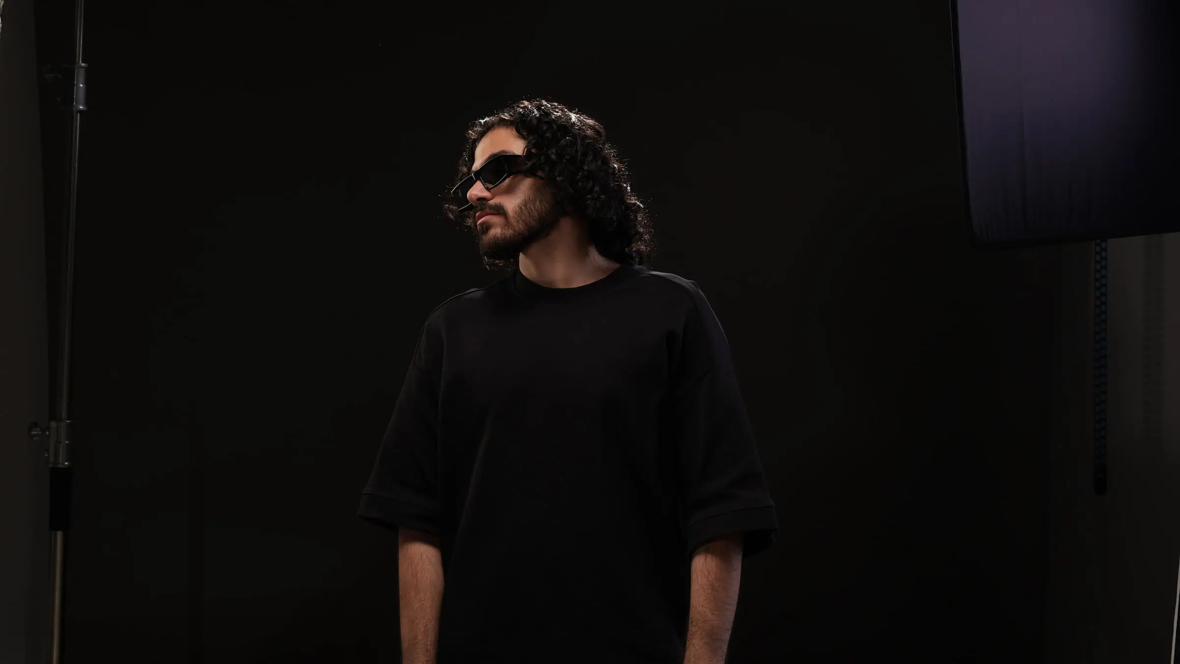 SOUL in a black studio, dark glasses, looking away from the camera